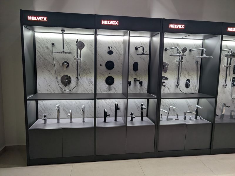 Row of Helvex wall modules displaying showers and faucets